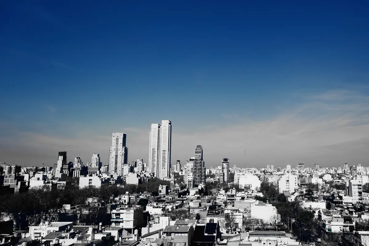 A wide view across the low rooftops of Palermo Hollywood with tall apartment towers rising under a deep blue sky